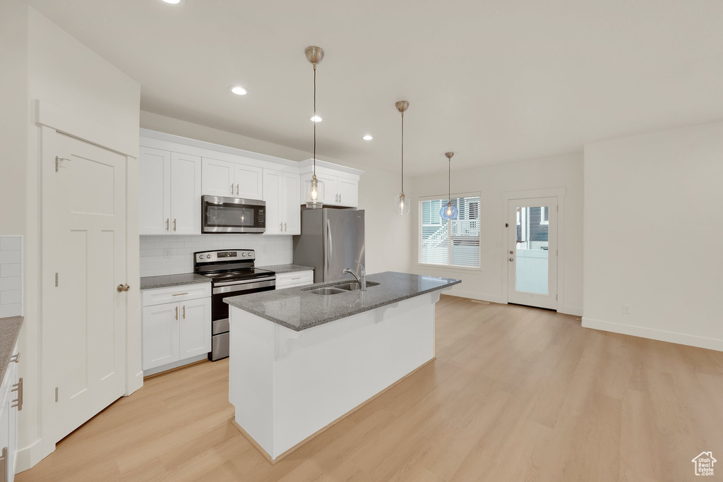 Kitchen featuring stainless steel appliances, light wood-type flooring, tasteful backsplash, white cabinets, and recessed lighting