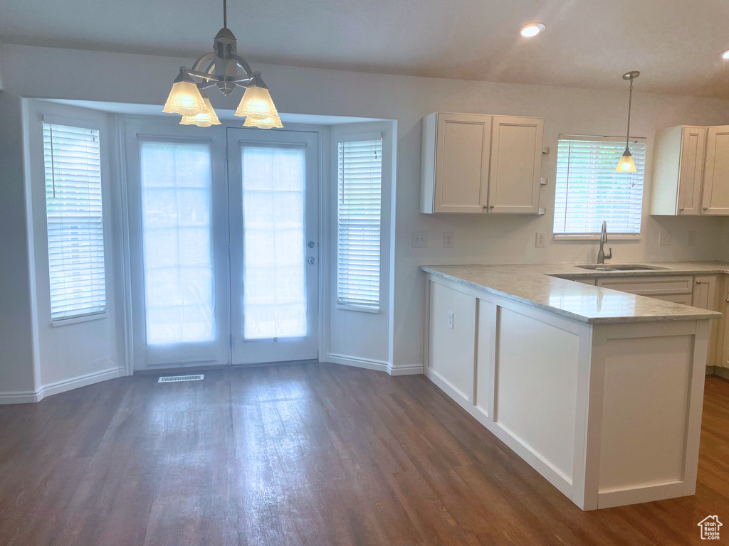 Kitchen featuring a sink, dark wood-type flooring, baseboards, white cabinetry, and a peninsula