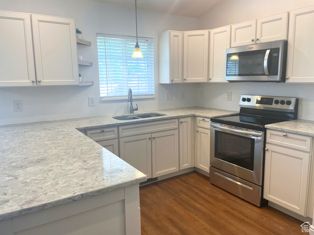 Kitchen featuring appliances with stainless steel finishes, a sink, white cabinets, decorative light fixtures, and dark wood-style flooring