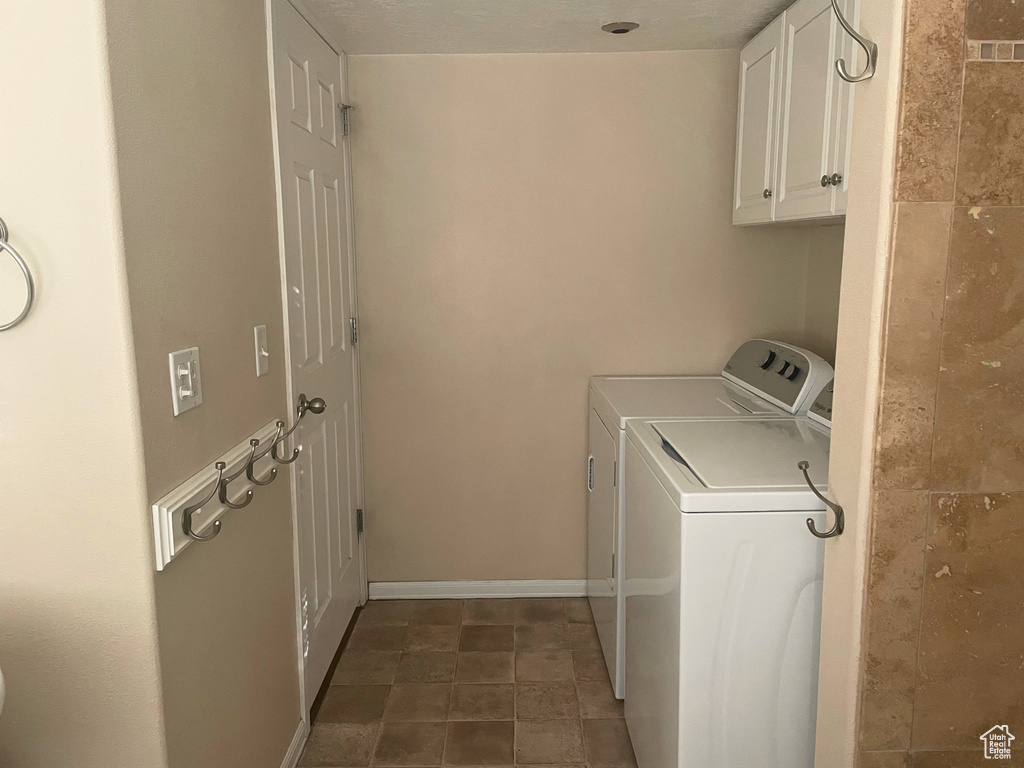 Washroom featuring washer and dryer, cabinet space, and baseboards