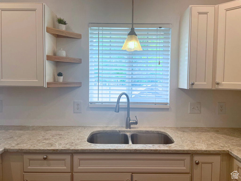 Kitchen featuring a sink, open shelves, white cabinets, and decorative light fixtures