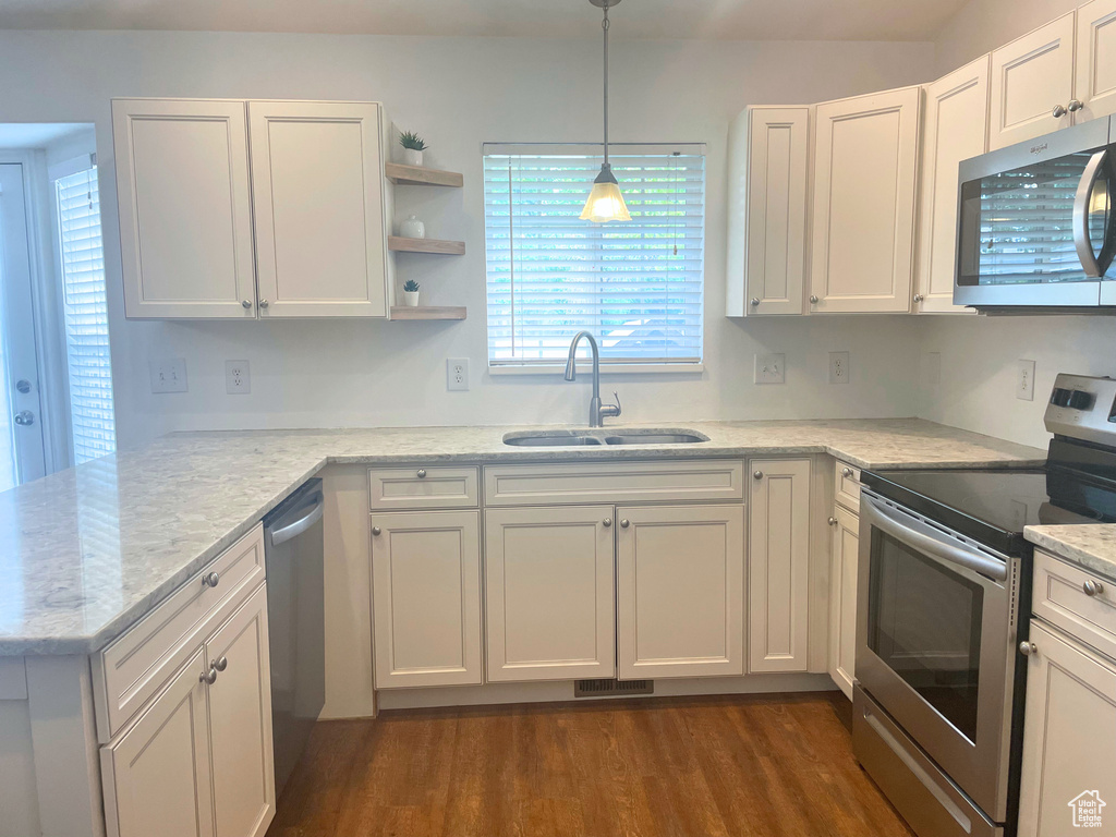 Kitchen featuring stainless steel appliances, a sink, white cabinetry, and dark wood-style floors