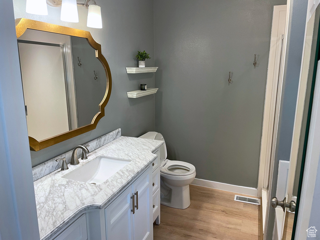 Bathroom with wood finished floors, baseboards, vanity, and toilet