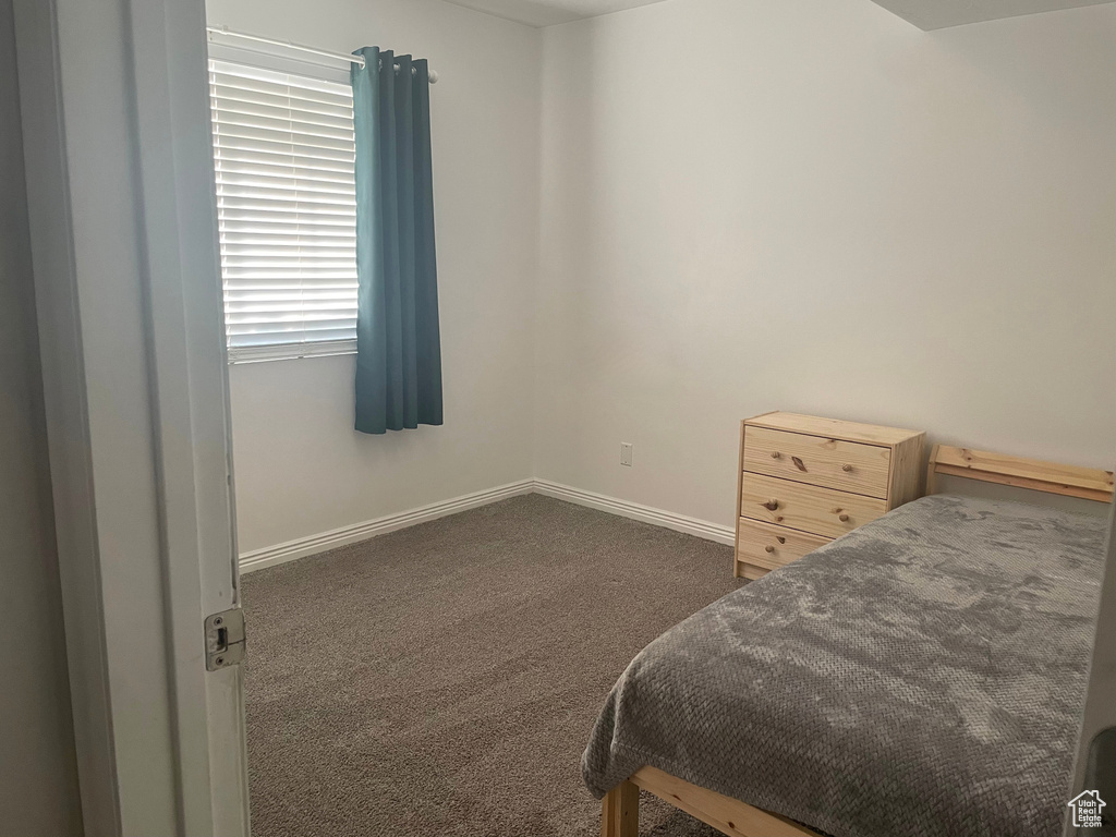 Bedroom with dark colored carpet and baseboards