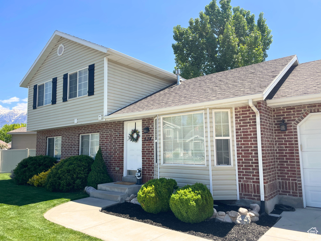 View of front of house with brick siding, roof with shingles, and a garage