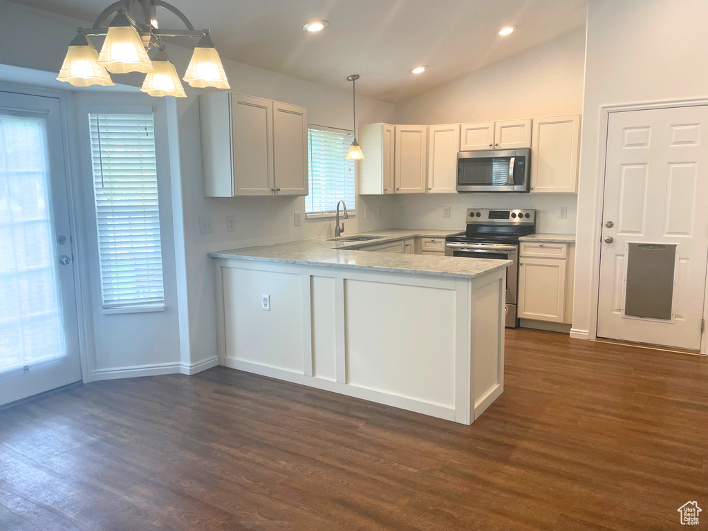 Kitchen featuring stainless steel appliances, dark wood-style floors, a peninsula, vaulted ceiling, and a sink