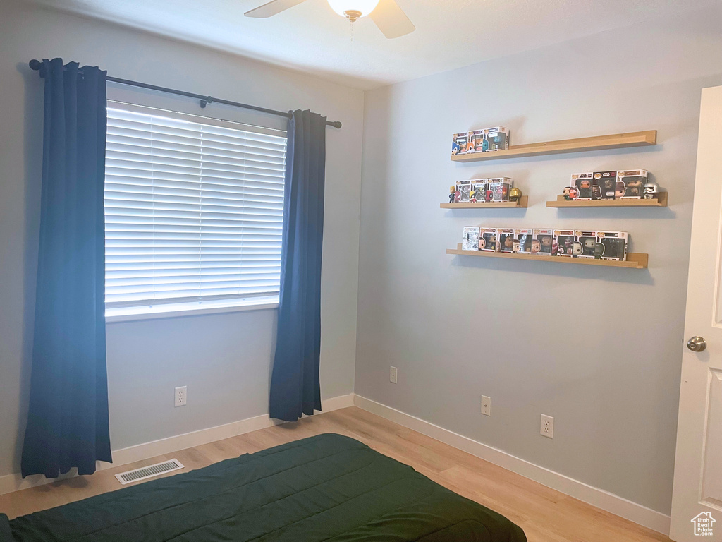 Bedroom with light wood-style floors, a ceiling fan, and baseboards