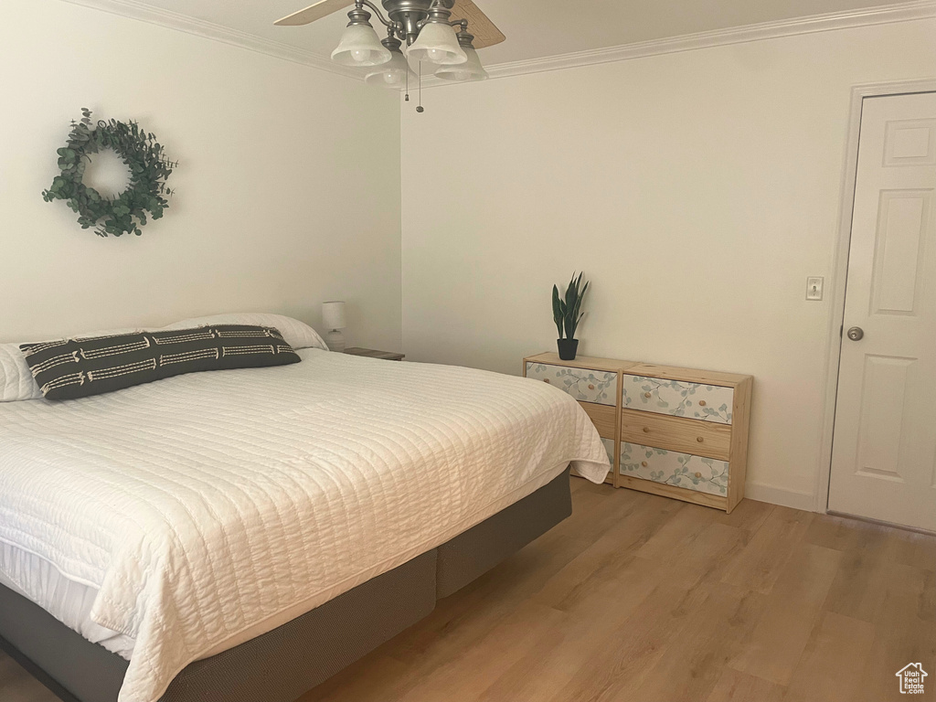 Bedroom with wood finished floors, ornamental molding, and a ceiling fan