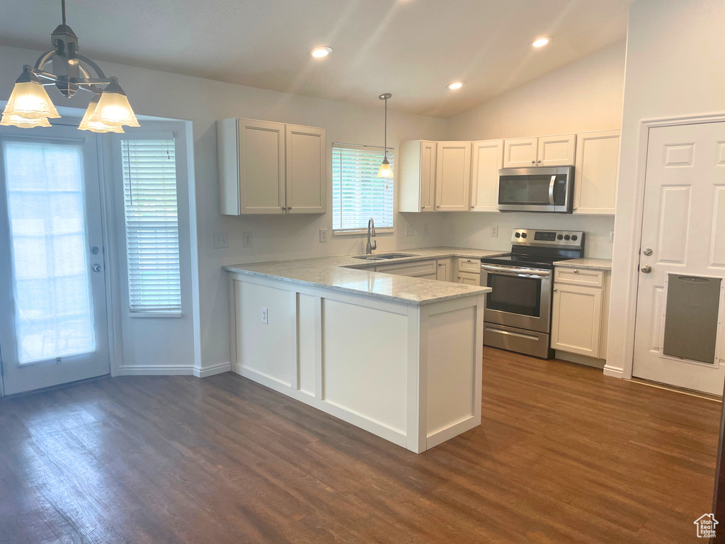 Kitchen featuring appliances with stainless steel finishes, a sink, a peninsula, dark wood-style flooring, and white cabinetry