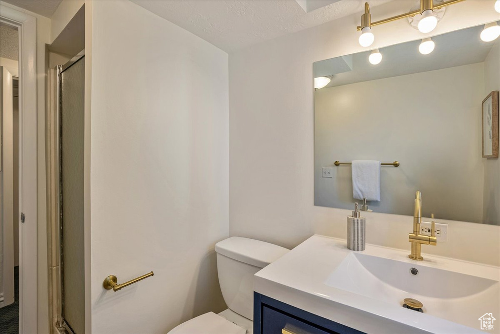 Full bath featuring toilet, a stall shower, and vanity