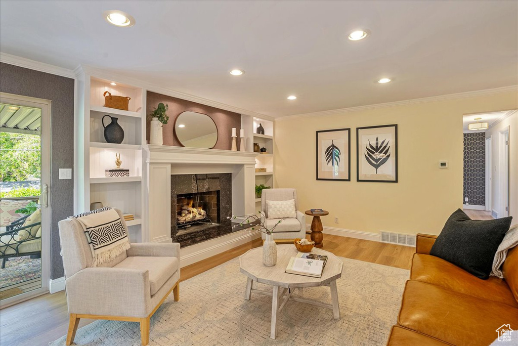 Living area featuring ornamental molding, baseboards, wood finished floors, a fireplace, and recessed lighting