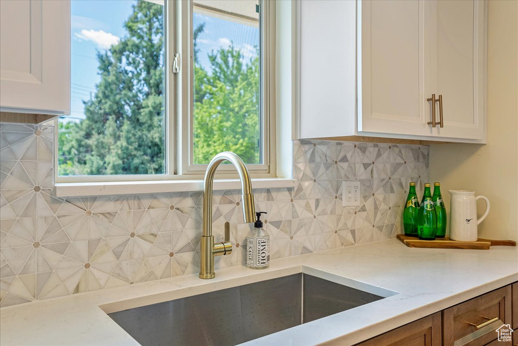 Kitchen featuring a sink, light stone countertops, white cabinetry, and healthy amount of natural light