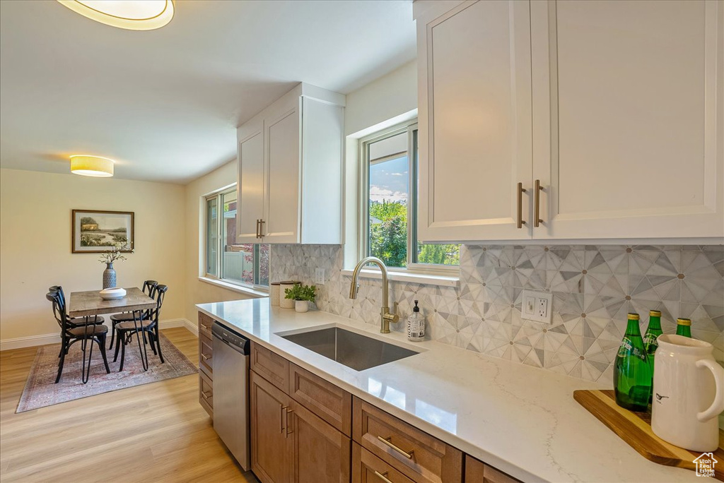 Kitchen with a sink, stainless steel dishwasher, and light wood finished floors