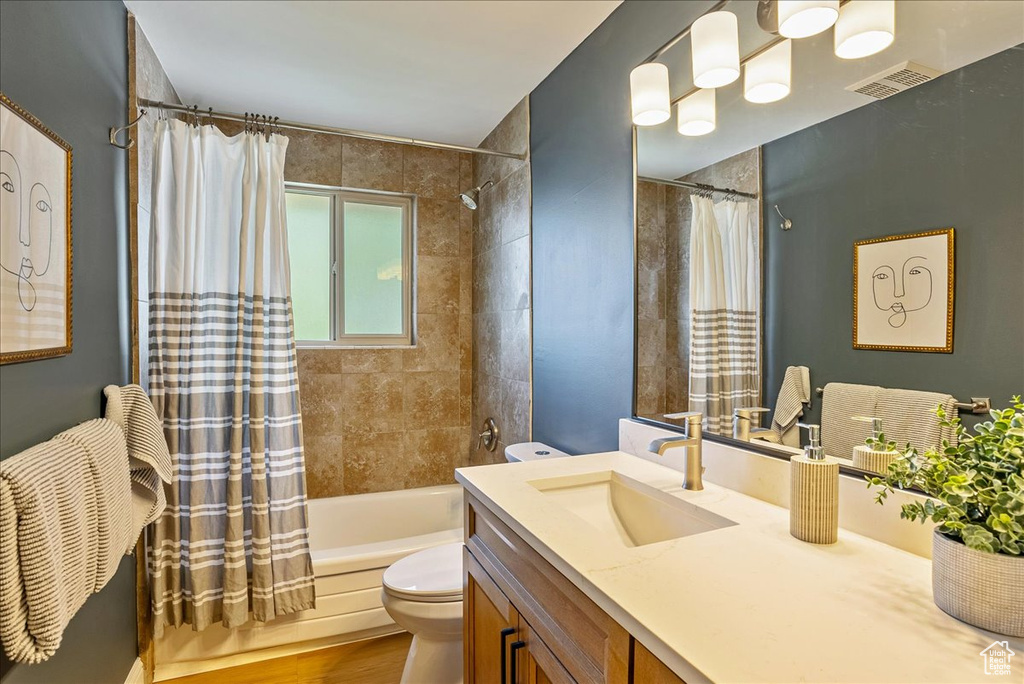 Bathroom with toilet, shower / bath combo with shower curtain, vanity, and wood finished floors