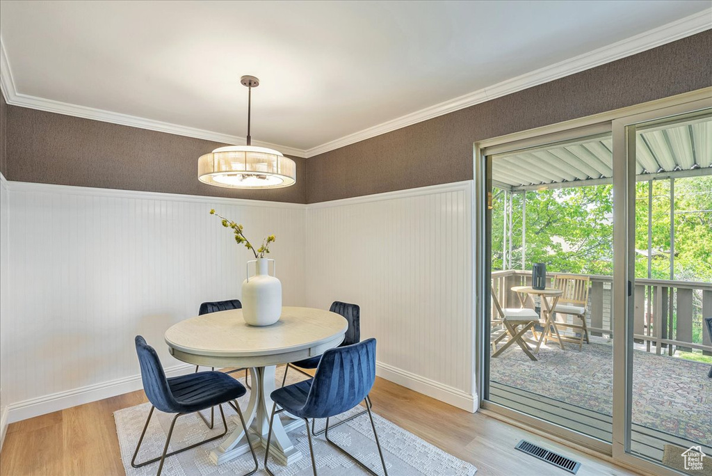 Dining area with light wood finished floors, baseboards, wainscoting, and crown molding