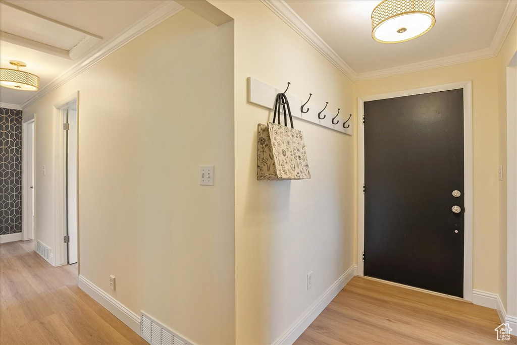 Hallway featuring light wood-type flooring, ornamental molding, and baseboards