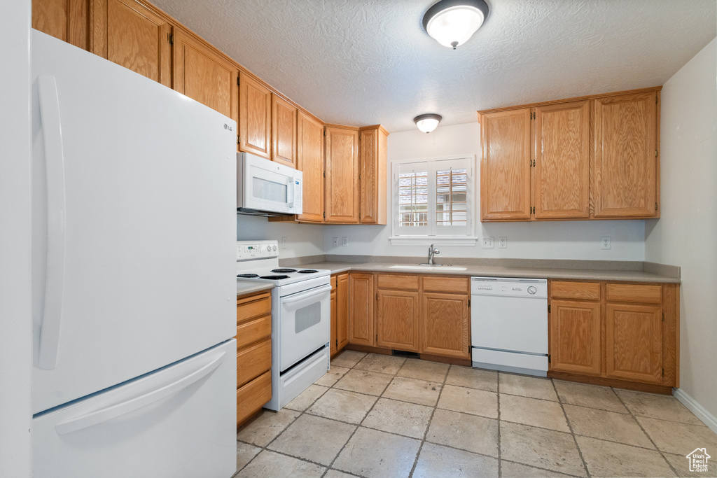 Kitchen with white appliances, a sink, light countertops, and a textured ceiling