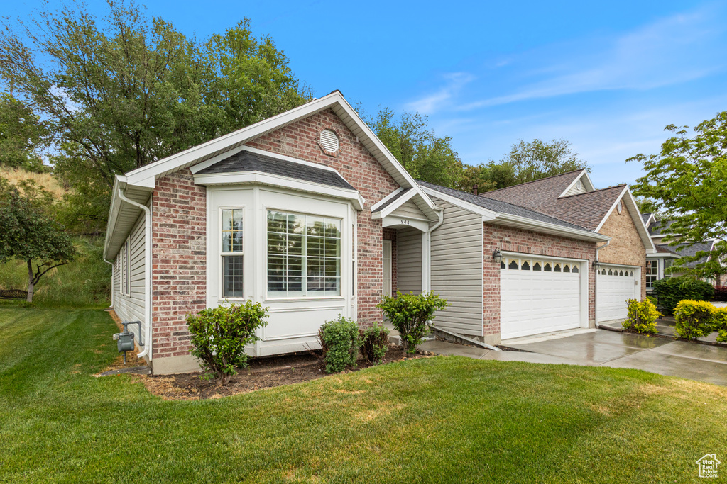 View of front of property with an attached garage, a front lawn, driveway, brick siding, and roof with shingles