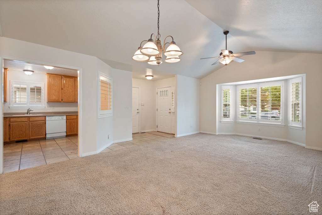 Unfurnished living room featuring light colored carpet, a sink, ceiling fan, lofted ceiling, and a chandelier
