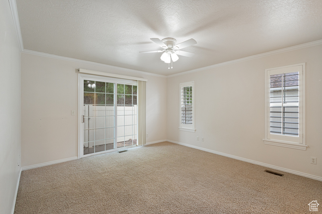 Carpeted spare room featuring ceiling fan, ornamental molding, and baseboards