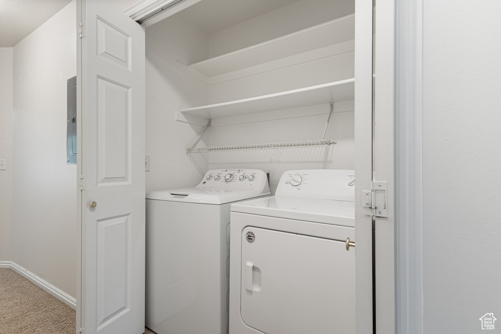 Laundry room with electric panel, washer and clothes dryer, carpet floors, and baseboards