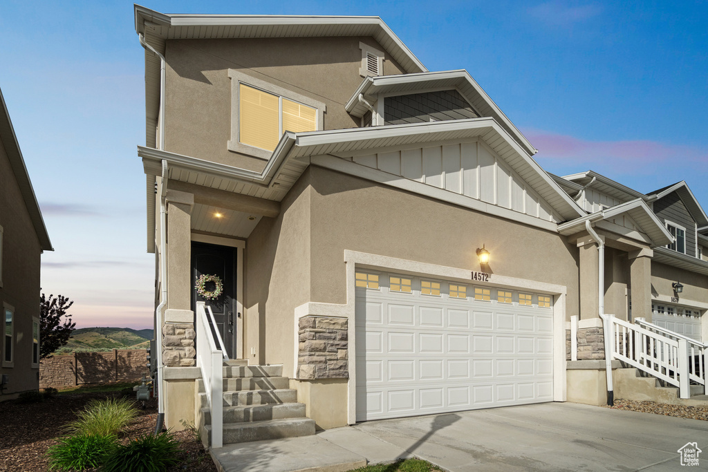 View of front of property featuring stone siding, stucco siding, and concrete driveway