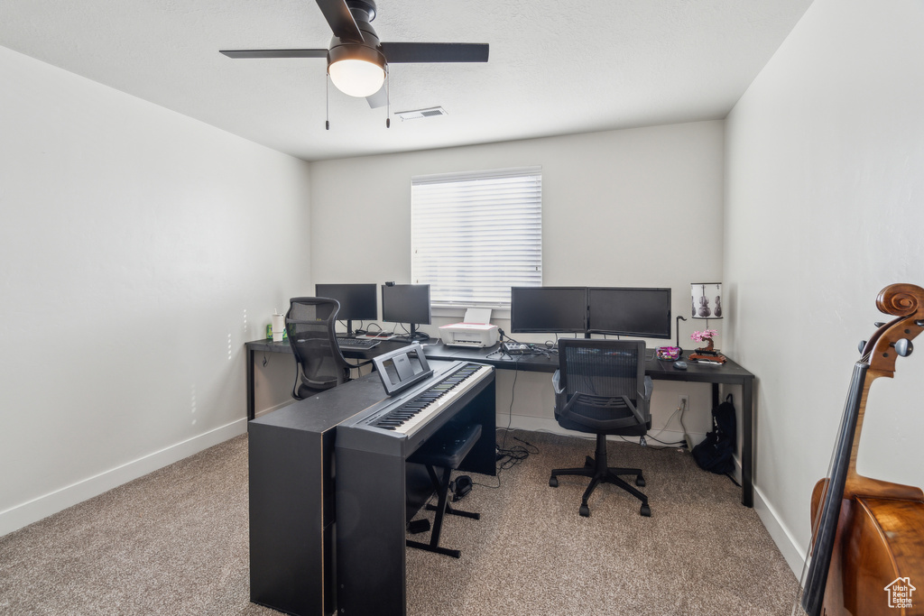 Carpeted office space with ceiling fan and baseboards