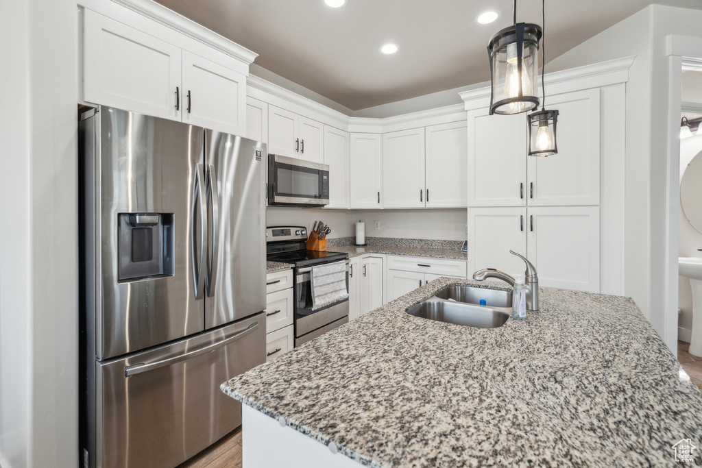 Kitchen featuring stainless steel appliances, a sink, white cabinets, light stone counters, and recessed lighting