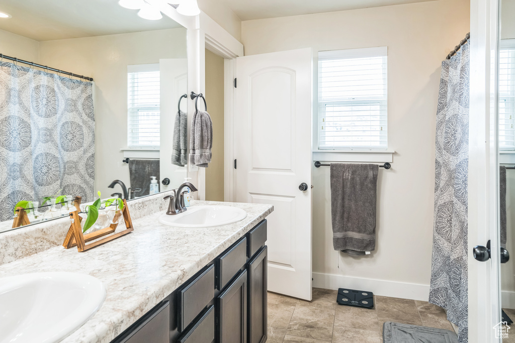 Full bathroom with double vanity, baseboards, and tile patterned flooring