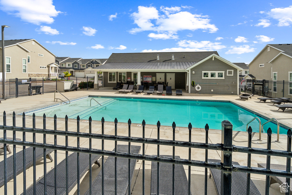 Community pool featuring a patio area, fence, and a residential view
