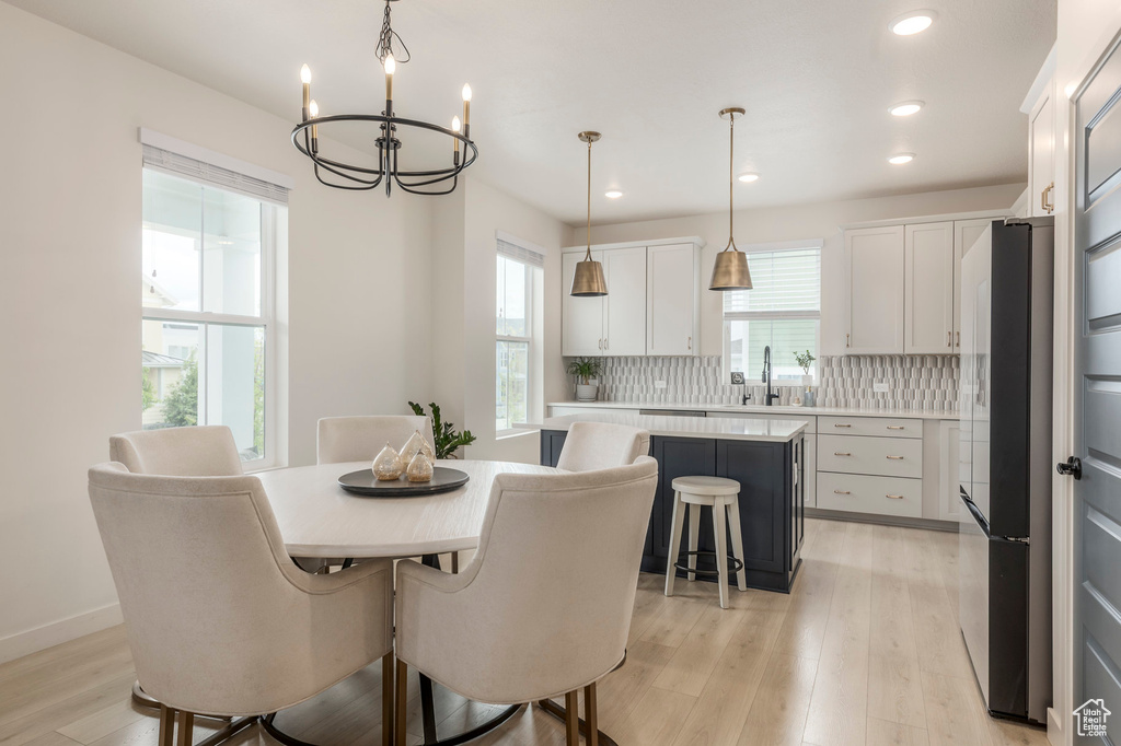 Dining room with plenty of natural light, a chandelier, light wood-type flooring, recessed lighting, and baseboards