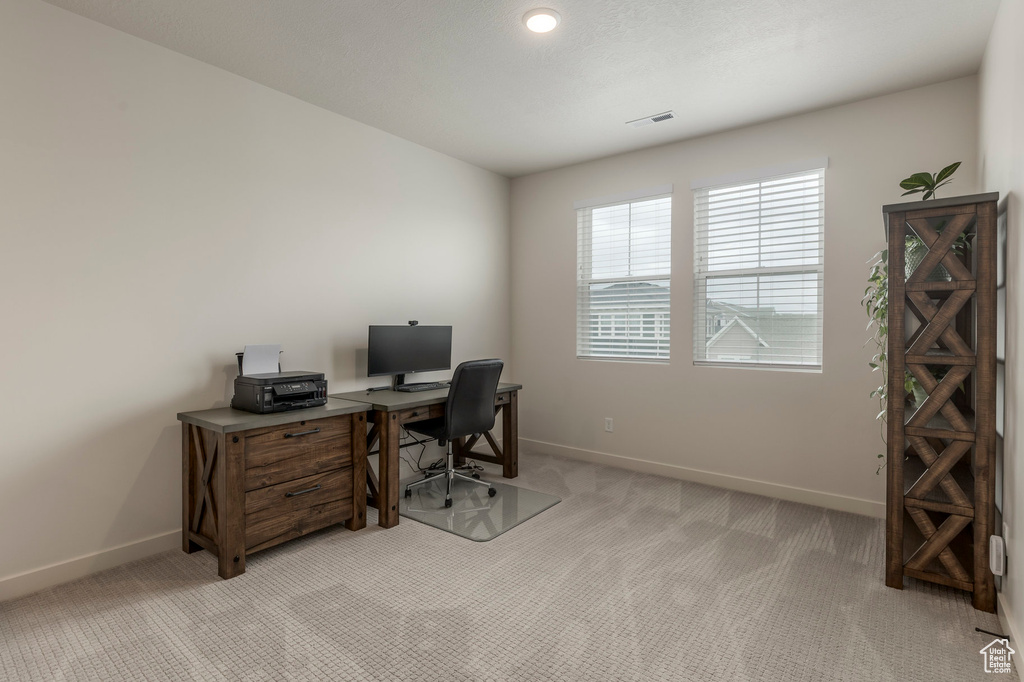 Home office with light colored carpet and baseboards