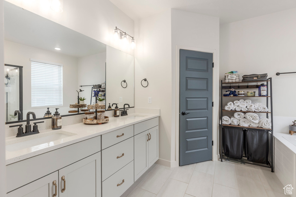 Bathroom featuring tile patterned flooring, double vanity, and a tub to relax in