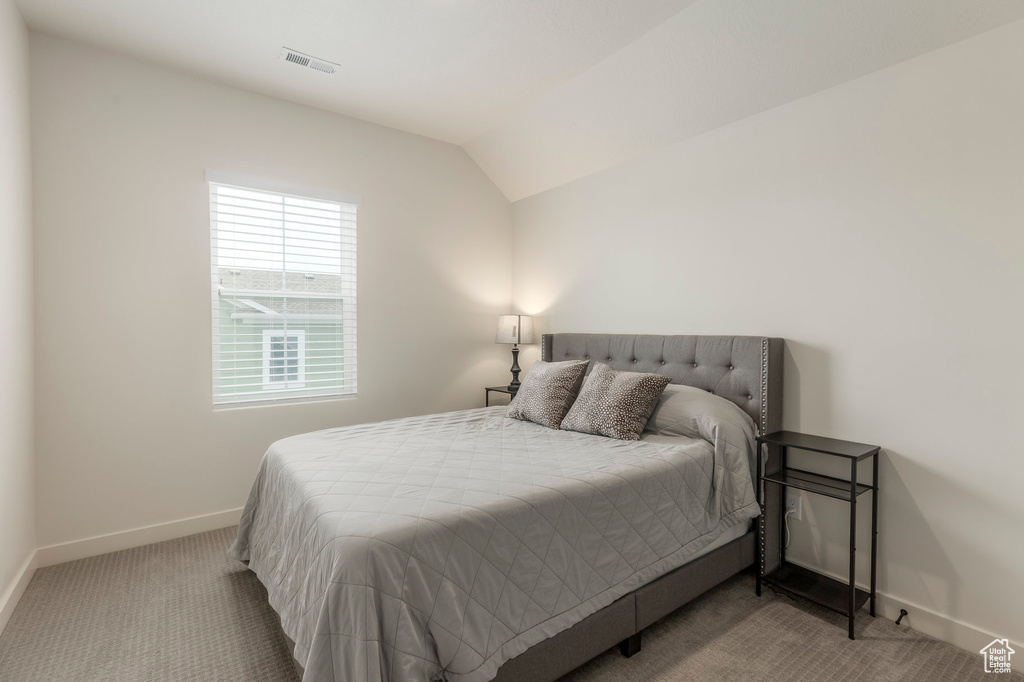 Carpeted bedroom featuring baseboards and lofted ceiling