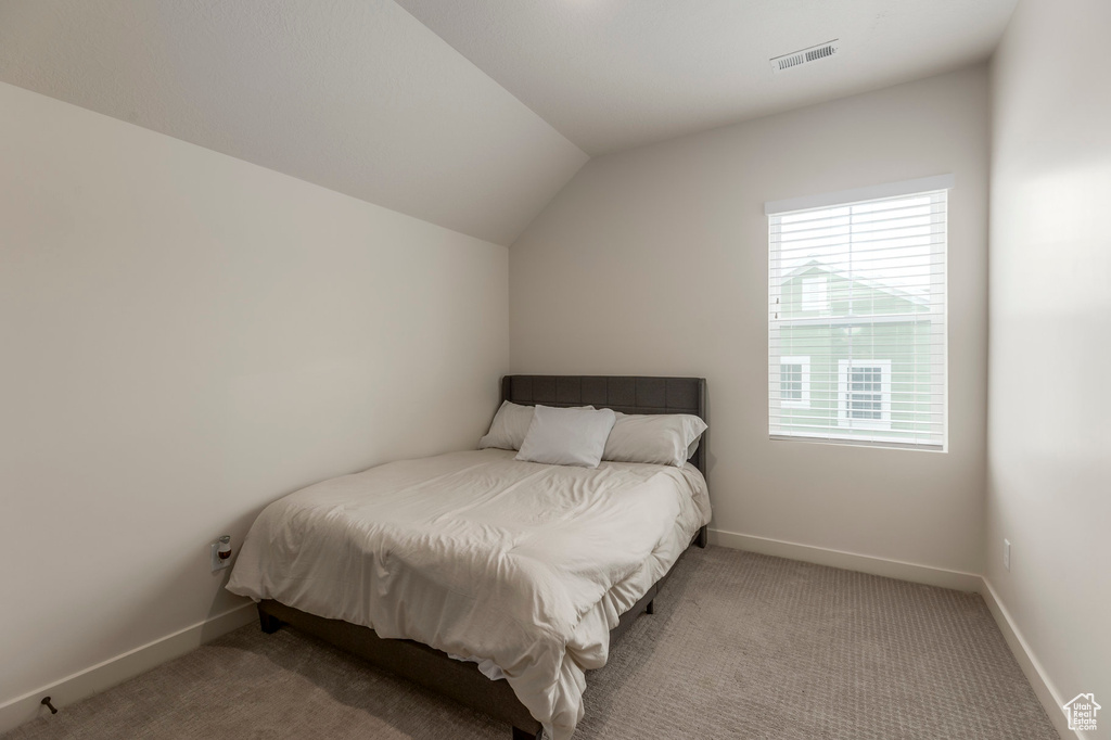 Bedroom featuring vaulted ceiling, baseboards, and carpet floors