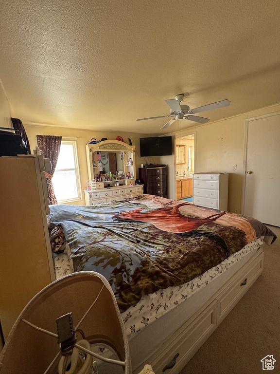 Carpeted bedroom featuring a textured ceiling and a ceiling fan