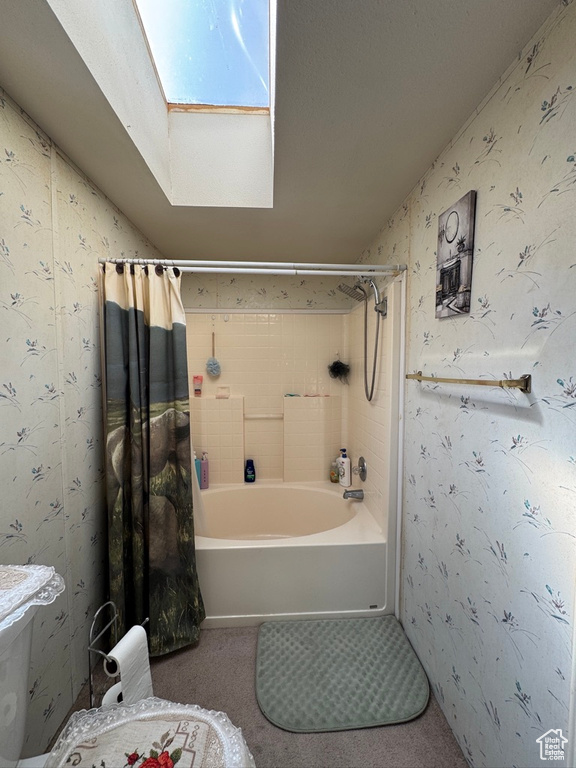 Bathroom with a skylight, wallpapered walls, and shower / tub combo with curtain