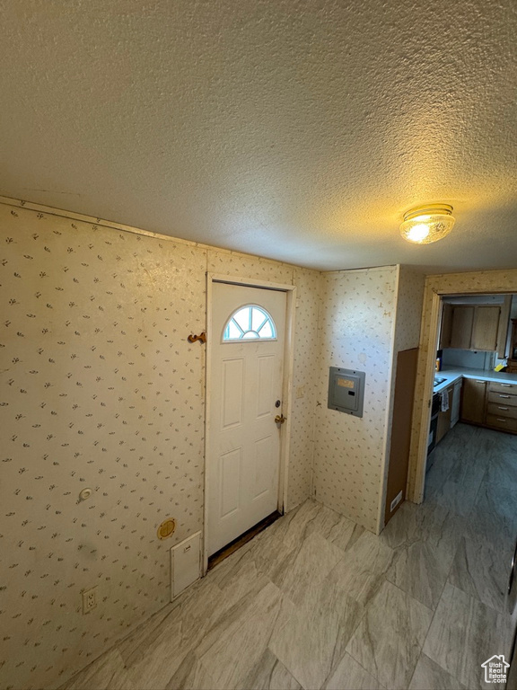 Foyer entrance with a textured ceiling and wallpapered walls