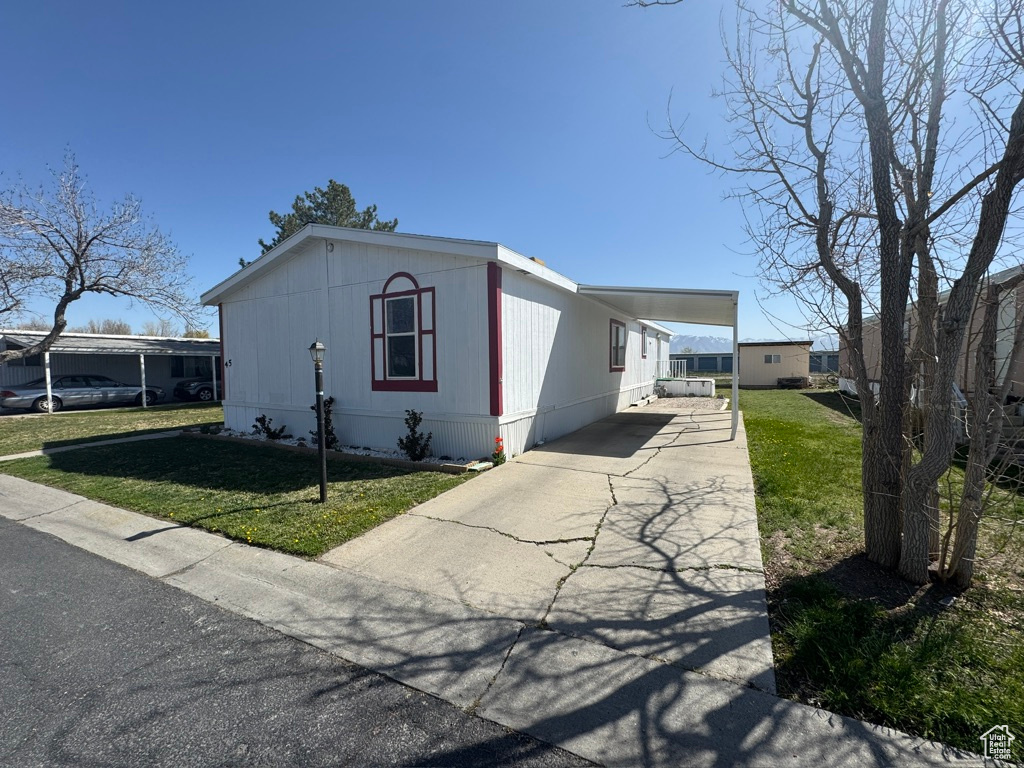 Manufactured / mobile home with driveway, a front lawn, and a carport