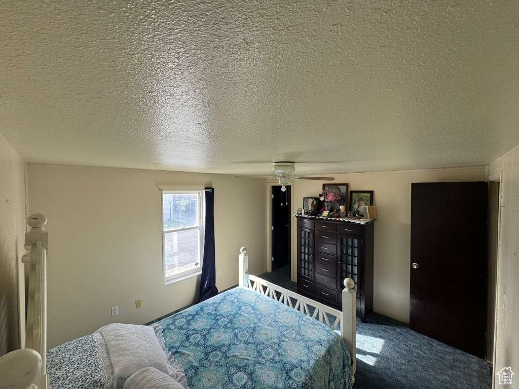 Bedroom with carpet, a textured ceiling, and a ceiling fan