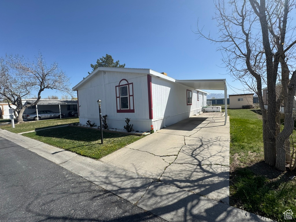 View of front of property featuring driveway, a front lawn, and an attached carport