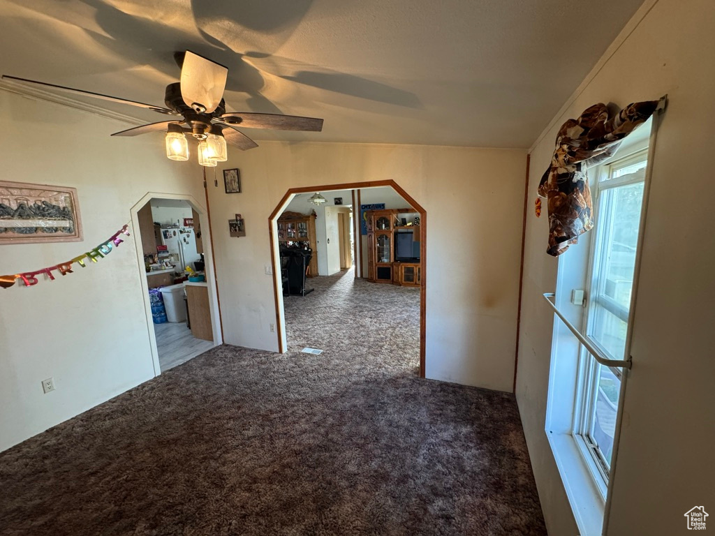 Unfurnished room featuring arched walkways, carpet floors, and a ceiling fan