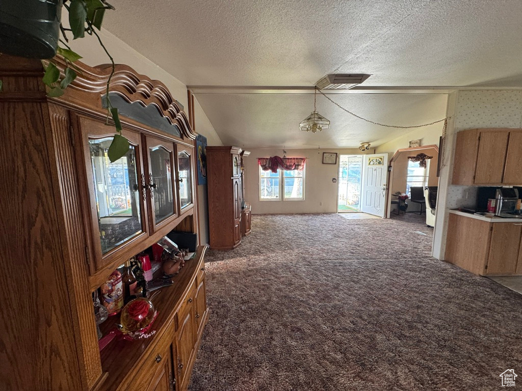 Interior space featuring a textured ceiling, carpet, and lofted ceiling