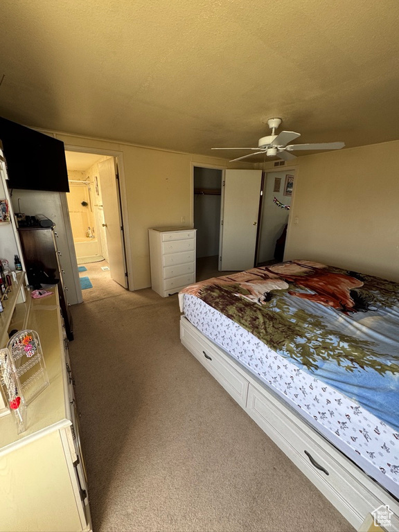 Bedroom with light carpet, a closet, ensuite bath, and a textured ceiling