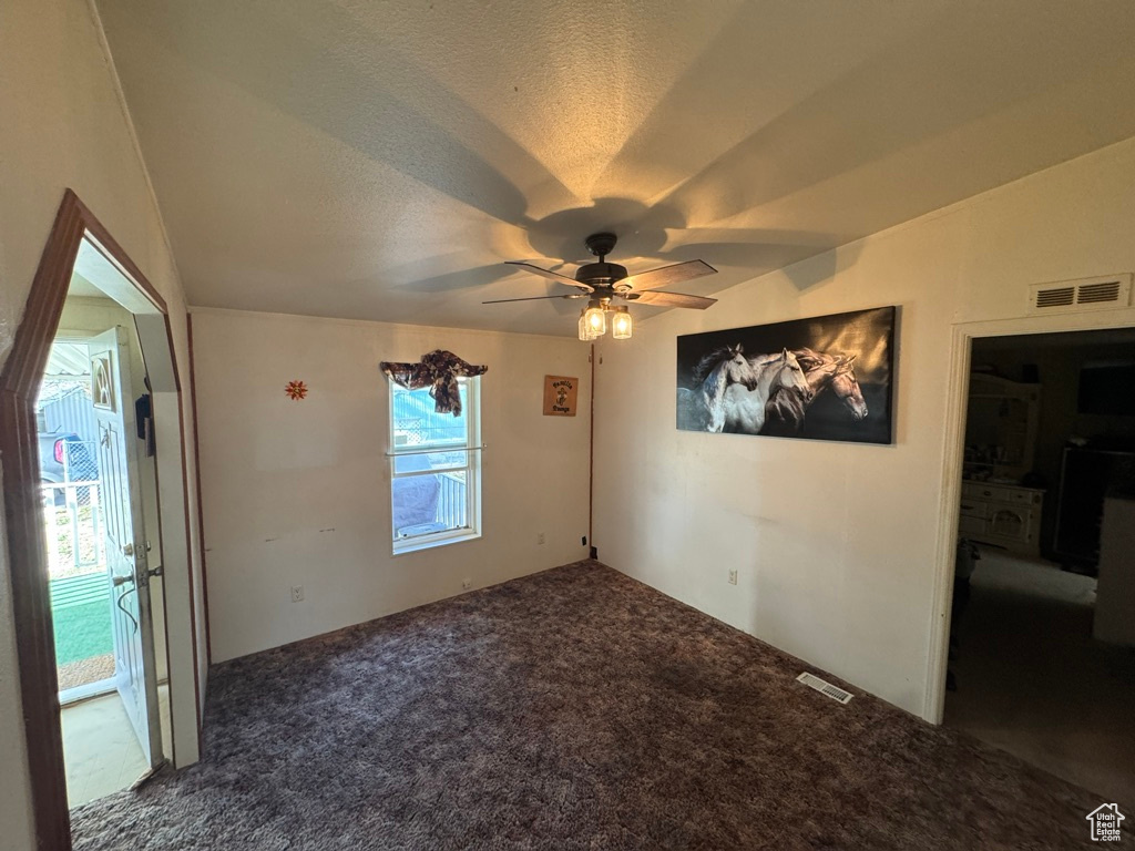 Spare room featuring carpet, ceiling fan, and a textured ceiling