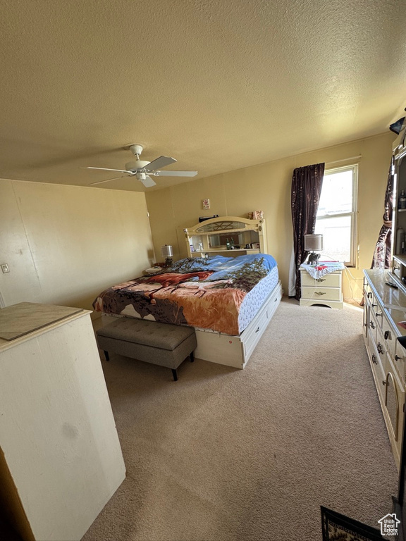 Carpeted bedroom featuring a textured ceiling and ceiling fan