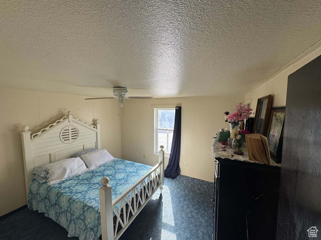 Carpeted bedroom featuring a ceiling fan and a textured ceiling