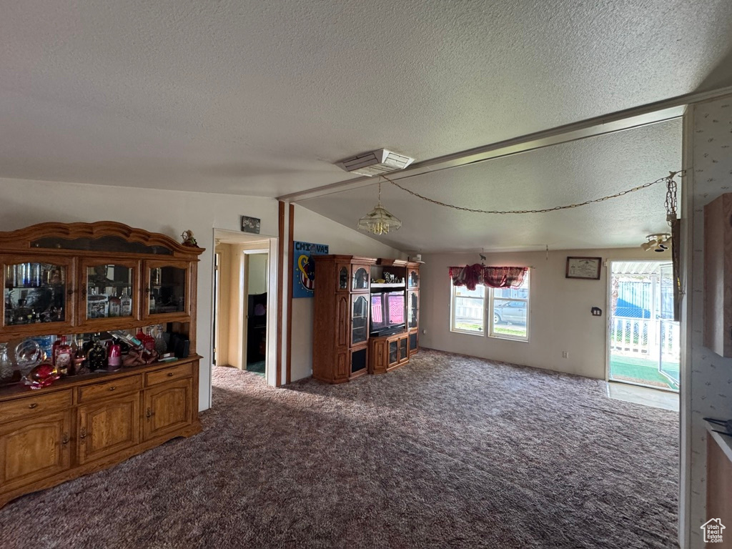 Carpeted dining room featuring a textured ceiling and lofted ceiling