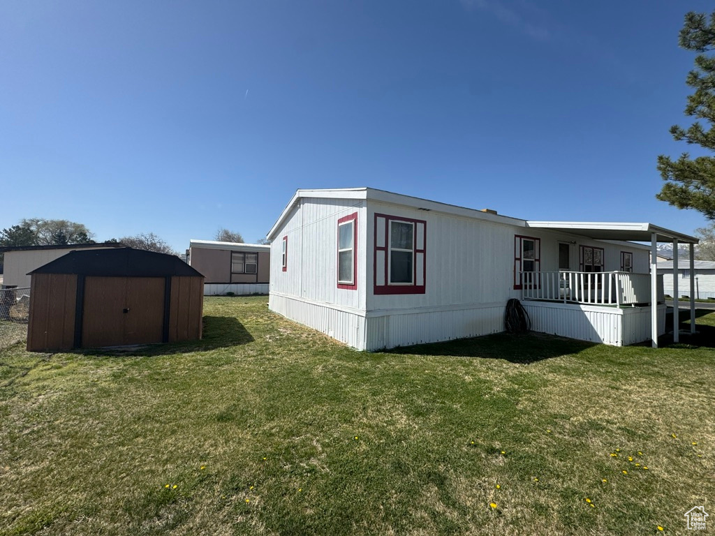 View of side of home featuring a storage unit, an outdoor structure, and a yard