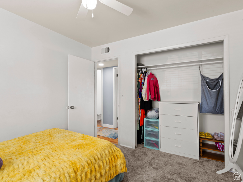 Carpeted bedroom featuring a closet and ceiling fan